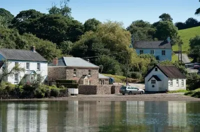 a house and a car parked next to a body of water at Riverside in Kea