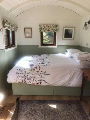 a large bed in a bedroom with two windows at Lovely Shepherds hut near St Ives Cornwall in Gwinear Road Station