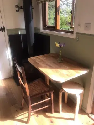 a wooden table with two chairs and a vase of flowers at Lovely Shepherds hut near St Ives Cornwall in Gwinear Road Station