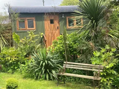 a bench in front of a small green house at Lovely Shepherds hut near St Ives Cornwall in Gwinear Road Station