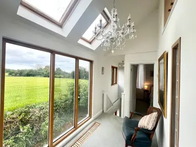 a living room with a chandelier and large windows at Trelean Lodge in Leedstown