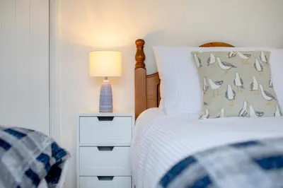 a bedroom with a bed with a lamp on a night stand at Beautiful Cottage nr Perranporth Private Parking in Perranzabuloe