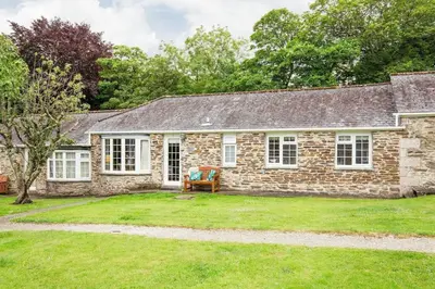 an old stone house with a lawn in front of it at Beautiful Cottage nr Perranporth Private Parking in Perranzabuloe