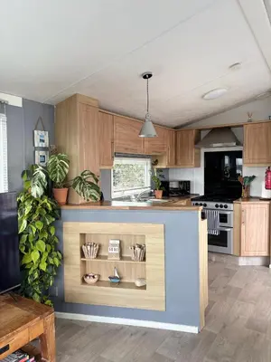 a kitchen with wooden cabinets and a counter top at Stylish Family Friendly 3-Bed Caravan Escape at Seven Bays Park in St Merryn