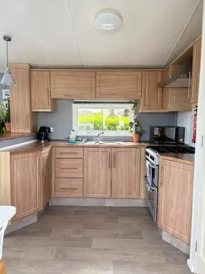 a kitchen with wooden cabinets and a window at Stylish Family Friendly 3-Bed Caravan Escape at Seven Bays Park in St Merryn