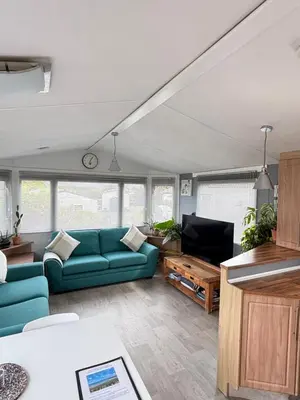 a living room with a blue couch and a tv at Stylish Family Friendly 3-Bed Caravan Escape at Seven Bays Park in St Merryn