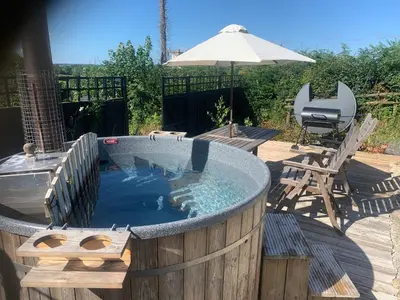 a hot tub sitting on a deck with an umbrella at Stable End in Liskeard