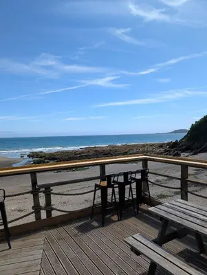 a deck with a picnic table and chairs on the beach at Luxury Sea View Chalet At Millendreath in Looe