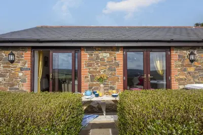 a stone cottage with a table in front of it at Hot Tub Bungalow - Close to Portreath - Free WiFi - Free Parking - Pet Friendly in Redruth