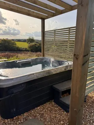 a jacuzzi tub sitting under a wooden roof at Stargaze at OLJU Lodges in Stithians