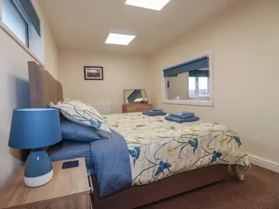 a bedroom with a bed with a blue lamp and a window at Kingfisher Lodge in St Austell