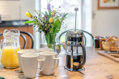 a coffee maker and cups on a wooden table at 3 Bed in Gwennap oc-g30876 in Gwennap