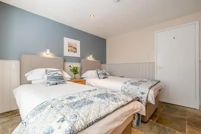 two beds in a room with blue walls at 2 Bed in Little Petherick oc-o30788 in Little Petherick