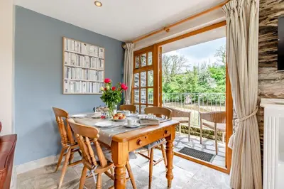 a dining room with a table and chairs and a balcony at 2 Bed in Little Petherick oc-o30788 in Little Petherick