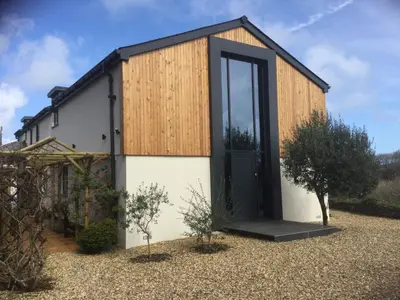 a small house with a black door in a yard at Lanteague Cornwall with stunning Sea Views in Gillan