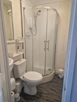 a bathroom with a toilet and a glass shower at cornish Choughs Inn in Camborne