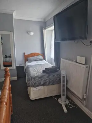 a bedroom with a bed with a large television on the wall at cornish Choughs Inn in Camborne