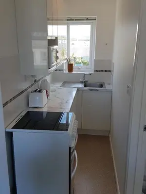a white kitchen with a sink and a stove at Ground Floor Chyreene in Phillack
