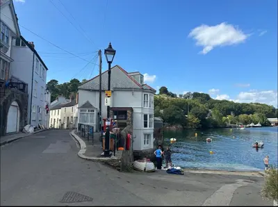 a building on the side of a river next to a street at The Slipway Suite Fowey Harbour & Parking 1 Min in Fowey