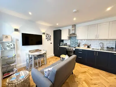 a living room with a couch and a kitchen at The Slipway Suite Fowey Harbour & Parking 1 Min in Fowey