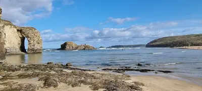 a beach with large rocks in the water at Ligger View in Perranporth