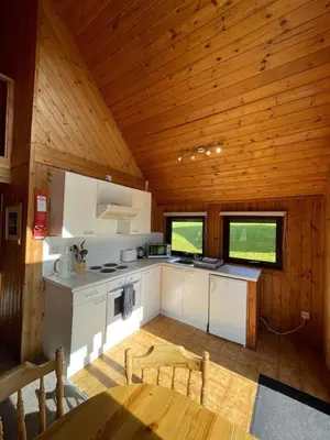 a kitchen in a cabin with a wooden ceiling at 3 Bedroom Lodge Lanteglos 21 in Lanteglos