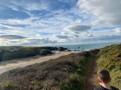 a boy standing on a hill looking at the beach at Padstow Holiday Base Bright Two Bedroom Lodge at Seven Bays in St Merryn