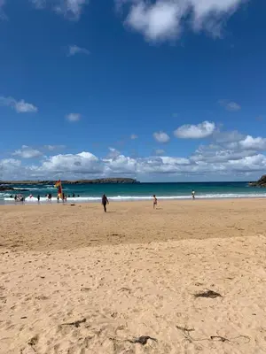a group of people walking on a beach at Padstow Holiday Base Bright Two Bedroom Lodge at Seven Bays in St Merryn