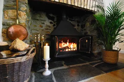 a stone fireplace with a candle in a room at Riverside farm cottage on private wildlife estate 3-bedrooms in Washaway