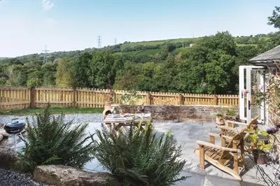 a patio with a table and chairs and a fence at Riverside cottage on private wildlife estate 2-bed in Washaway