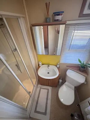 a bathroom with a toilet and a sink and a shower at Seaside Escape 2-Bed Caravan at Seven Bays Park in St Merryn