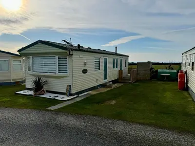 a tiny house in a yard next to a fence at Meadow & Tide in St Merryn