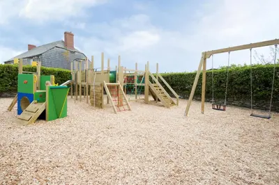 a playground with a slide and a swing set at Meadow & Tide in St Merryn