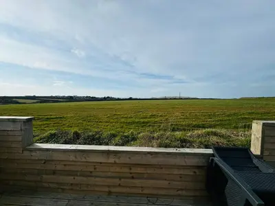 a view of a field from a porch with a bench at Meadow & Tide in St Merryn
