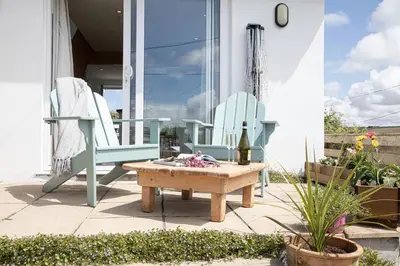 a patio with two chairs and a table and a bottle of wine at One bed spectacular ocean views, walk to the beach in Truro