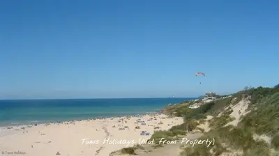 a group of people on a beach flying a kite at B12 Branksome, Riviere Towans in Hayle