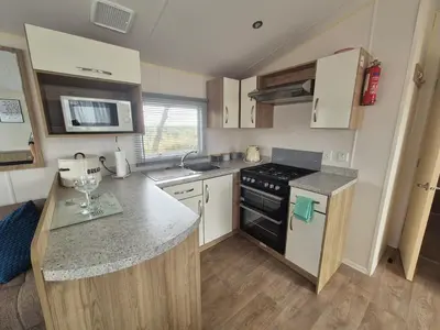 a small kitchen with a stove and a counter top at Cosy Perranporth caravan, Cornwall in Perranzabuloe