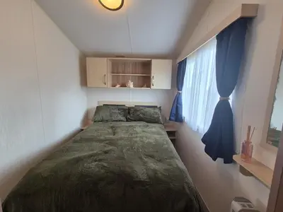 a small bedroom with a bed and a window at Cosy Perranporth caravan, Cornwall in Perranzabuloe