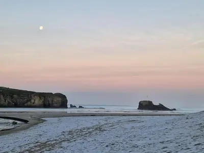 a beach with a lighthouse in the distance at Cosy Perranporth caravan, Cornwall in Perranzabuloe