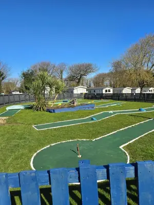 a golf course in a park with a blue fence at Cornwall Caravan Retreat 3 Crantock in Crantock