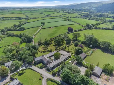 an aerial view of a field with trees and buildings at 3 Bed in Launceston oc-l31001 in Lewannick
