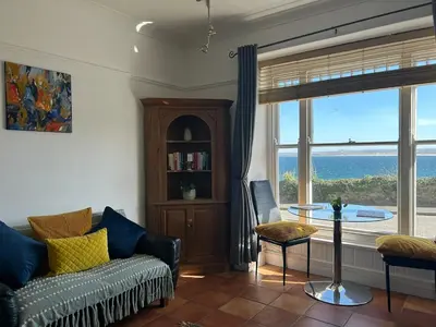 a living room with a couch and a view of the ocean at 'Rocks' Sea Views with free parking in St Ives in St Ives