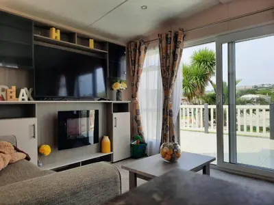 a living room with a couch and a large window at Luxury 6 berth caravan full decking in Saint Columb Minor