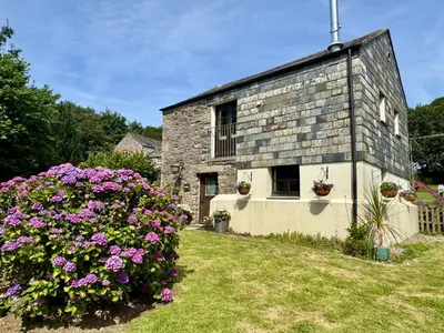 an old stone building with flowers in front of it at The Mill in Lostwithiel