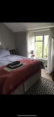 a bedroom with a bed with a red blanket and a window at Greenbank Farm in Falmouth