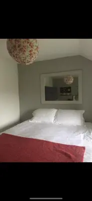 a bedroom with a white bed with a red blanket at Greenbank Farm in Falmouth