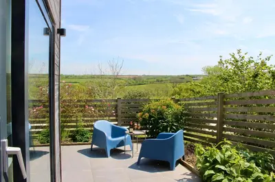 a patio with chairs and a table and a fence at Cicero's Lodge in Padstow