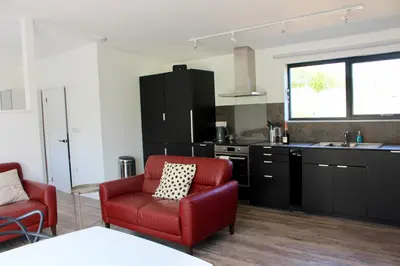 a living room with a red chair and a kitchen at Cicero's Lodge in Padstow