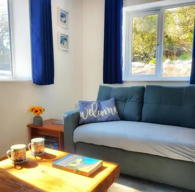 a living room with a blue couch and a table at Heart of Kernow Holiday Home in Bugle