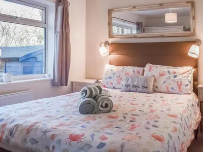 a bedroom with a bed with a large window at Low Tide in Looe